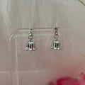 Silver bell-shaped earrings on a clear stand with a light background
